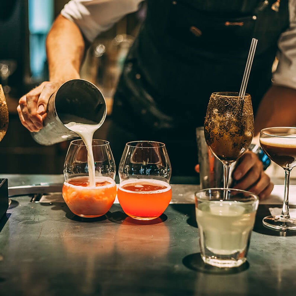 Image showcasing the art of mixology and crafted cocktails by Signature Chef Cy, featuring a bartender meticulously preparing personalized libations tailored to individual preferences, reflecting a symphony of flavors and mixology creativity.