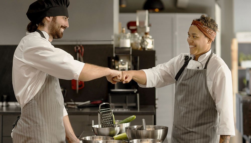 Image depicting a collaborative culinary environment at Signature Chef Cy, showcasing chefs working together to refine cooking techniques, enhance presentation, and ensure consistent execution of menu items, emphasizing culinary excellence and expertise.